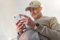 Close up young caucasian man in baseball cap looking and using mobile smart phone at home. Facetime video calling with Royalty Free Stock Photo