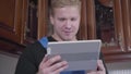 Close-up of young caucasian redhead man sitting with tablet and drinking tea or coffee. Unscrupulous repairman resting