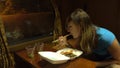 CLOSE UP: Young Caucasian woman eating dinner while travelling by night train.