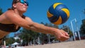 CLOSE UP: Young woman falls into the sand while striking ball with her hands. Royalty Free Stock Photo