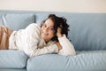 Close up of young Caucasian woman laying down on blue sofa indoor, fell asleep in casual outwear