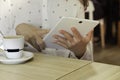 Young caucasian woman`s hands using a white tablet pc to telework while having coffee. Woman looking at multimedia