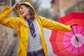 Close-up of a young cheerful woman in a yellow raincoat who is enjoying while listening to the music and walking the city on a