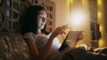 Close-up of young concentrated woman using tablet and watching online news lying in bed at home at night Royalty Free Stock Photo