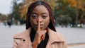 Close-up young confident mysterious african american woman standing outdoors showing silence gesture puts finger to Royalty Free Stock Photo
