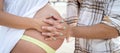 Close up of young couple hands holding together pregnant woman belly. Awaiting baby, pregnancy and family concept. Royalty Free Stock Photo