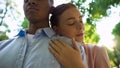 Close-up of young couple in park, teen girl leaning on boyfriends shoulder, love