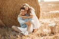 Happy couple sitting on bale in farmland Royalty Free Stock Photo