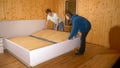 CLOSE UP: Young couple works together to assemble a large bed in their new home. Royalty Free Stock Photo