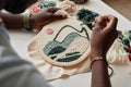 Close-up of young creative male artisan creating embroidery on canvas