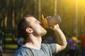 Close up young exhausted athlete drinking and pouring fresh water to refresh during running trail