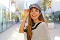 Close up of young fashion woman holding baker boy hat in shopping mall. Young pretty trendy girl posing in street with fashion