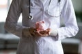 Close up young female doctor holding pink piggy bank Royalty Free Stock Photo