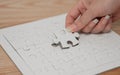 Close up of young female hand with long fingernails is placing white puzzle in last gap in the middle of the board to complete it Royalty Free Stock Photo