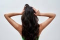 Close up of young female model posing against light background, showing off her healthy long dark brown hair Royalty Free Stock Photo