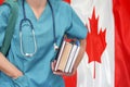 Student doctor with stethoscope and books in hand on Canada flag background. Nurse, Student, Education