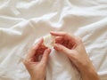 Close up. A young girl holds a condom in a hand in a white bed. The concept of sex and eroticism. Royalty Free Stock Photo