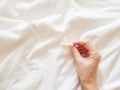 Close up. A young girl holds a condom in a hand in a white bed. The concept of sex and eroticism. Royalty Free Stock Photo