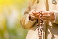 Close up young girl praying and holding a wooden rosary as symbol of belief and faith in Jesus Christ and eternal life Royalty Free Stock Photo