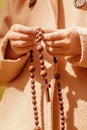 Close up young girl praying and holding a wooden rosary. Vertical image Royalty Free Stock Photo