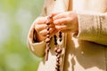 Close up young girl praying with wooden rosary. Horizontal image Royalty Free Stock Photo