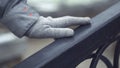 Close-up of young girl`s hand sliding over railing. Hand in grey glove touches railing outdoors in cold weather Royalty Free Stock Photo