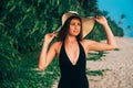 Close-up of a young girl in a swimsuit on the background of an empty white beach and a jungle admiring the sea, smiling Royalty Free Stock Photo