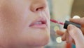 Young makeup artist applying lipstick on model`s lips. Royalty Free Stock Photo