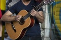 Close up of young giving a concert with guitar on the street. She leaned her back against the wall