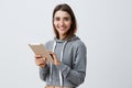 Close up of young good-looking joyful caucasian girl with dark long hair in gray sporty hoodie smiling with teeth