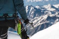 Close up A young guy climber holds in his hand an ice-ax standing on a summit high in the mountains. Extreme sport Royalty Free Stock Photo