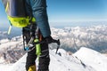 Close up A young guy climber holds in his hand an ice-ax standing on a summit high in the mountains. Extreme sport Royalty Free Stock Photo