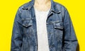 Close-up of young guy, wearing denim jacket and white shirt on yellow background. Royalty Free Stock Photo