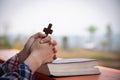 Close up young hands holding wooden cross over holy bible and praying. christian concept Royalty Free Stock Photo