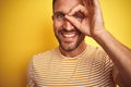 Close up of young handsome man wearing casual t-shirt over yellow isolated background doing ok gesture with hand smiling, eye Royalty Free Stock Photo