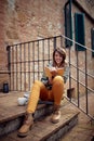 Close-up of a young handsome woman who is sitting on the stairs and reading a book. City, outside, rest