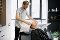 Close up of a young happy beautiful woman smiling to the camera while professional hairdresser wrapping her wet hair in