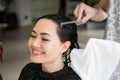Close up of a young happy beautiful woman smiling to the camera while professional hairdresser wrapping her wet hair in