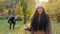 Close-up young happy smiling girl standing outdoors holding seedling in hand man digging hole for planting tree in Royalty Free Stock Photo