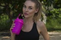 Close up of young healthy female wearing black exercise clothing holding pink shaker in her hand Royalty Free Stock Photo