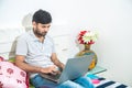 Close up of Young indian man busy working on his laptop doing office work while relaxing on bed in bedroom, freelancer working Royalty Free Stock Photo