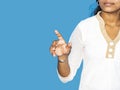 Close up of a young indian woman hand pointing finger as touching screen, isolated on blue background