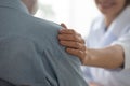 Young happy female doctor putting hand on old pensioner's shoulder. Royalty Free Stock Photo