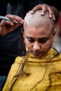Close-up of young lady devotee getting tonsured or head shaving ritual in Thaipusam Festival.