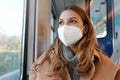 Close up of young lady wearing protective medical mask KN95 FFP2 on public transport looking through the window Royalty Free Stock Photo