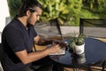 Close-up of a young latino man writing in a note pad with succulent plants in the table Royalty Free Stock Photo