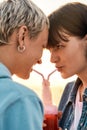 Close up of young lesbian couple looking at each other, drinking from one glass bottle with the straw, Two women Royalty Free Stock Photo