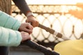 Close up of young loving family hands holding baby pram by the lake. Parents with stroller in autumn park on sunset. Love, parenth Royalty Free Stock Photo