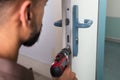 Carpenter Installing Door Lock With Wireless Screwdriver