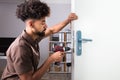 Carpenter Installing Door Lock With Wireless Screwdriver Royalty Free Stock Photo